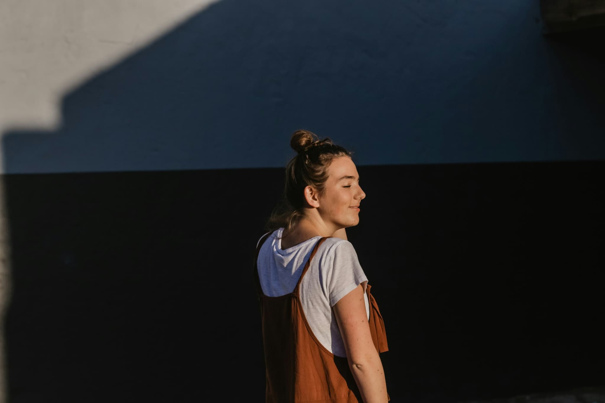 Woman pausing in warm evening light against a blue wall